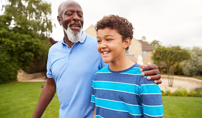 older senior man walking smiling younger smiling boy with arm around shoulder