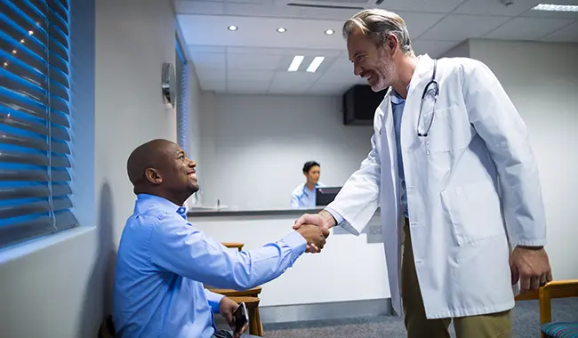 patient sitting shaking hands with doctor