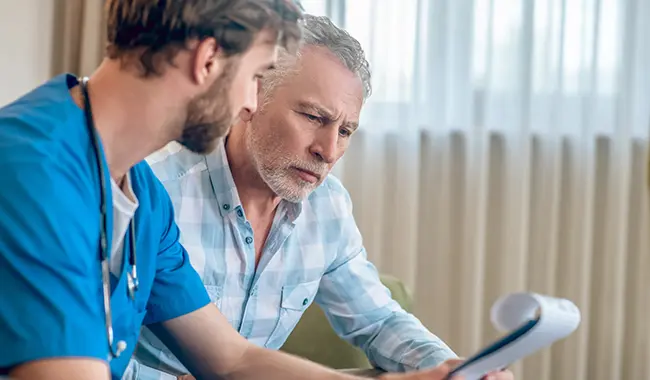 patient and medical professional reviewing paper pad with somber faces