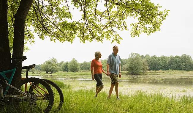 middle age couple walking outside by creek